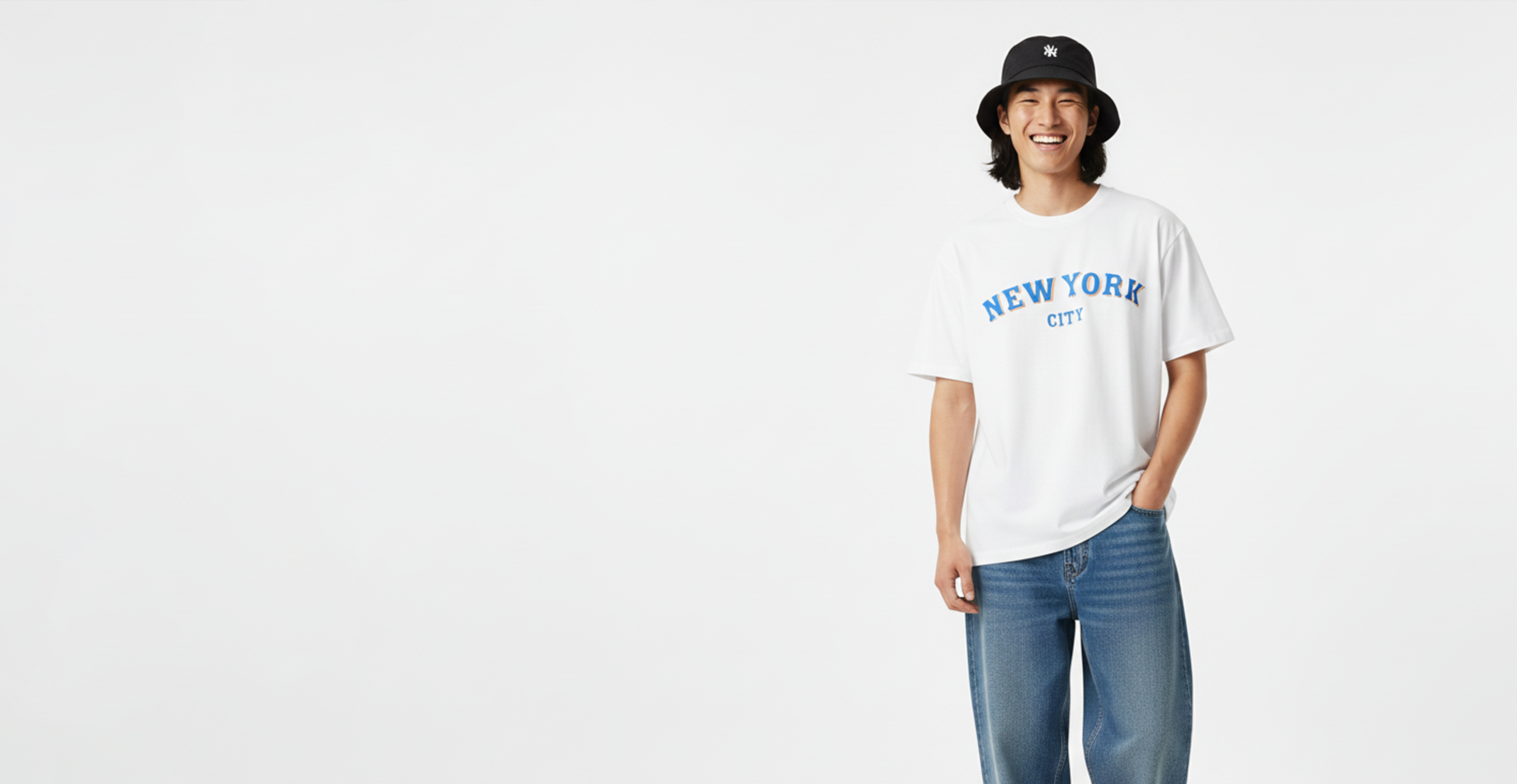 Asian man wearing a bucket hat and a white tshirt with "new york city" written on it.
